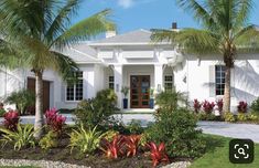 a white house surrounded by palm trees and flowers