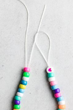 two necklaces made out of plastic beads on a white surface with string attached to them