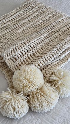 two white pom - poms laying on top of a bed next to a blanket