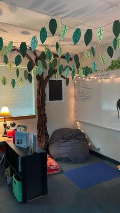 a room with a tree, bed and desk in it