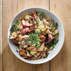 a white bowl filled with vegetables on top of a wooden table next to a fork