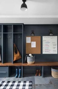 a wooden bench sitting under a light next to a wall mounted dry erase board and coat rack