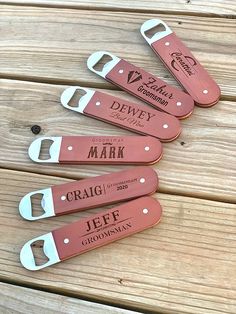 four personalized leather bottle openers on top of a wooden table