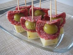 small appetizers with olives and meat are on a glass platter, ready to be eaten