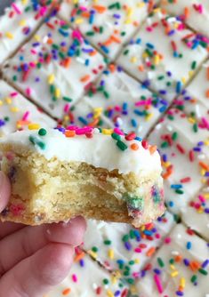 a hand holding a half eaten cake with sprinkles on it's side