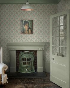 an old fashioned fireplace in a room with floral wallpaper and a painting on the wall