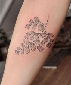 a black and white photo of a leaf tattoo on the arm