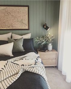 a bed with pillows and blankets on it in front of a map hanging over the headboard