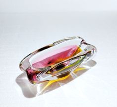 a glass dish sitting on top of a white table next to a yellow and pink object