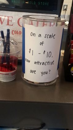 a cup with a note attached to it sitting on a counter next to a sign