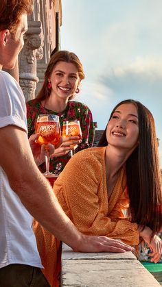 two women and a man are holding wine glasses