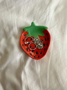 a red strawberry shaped brooch with black dots and a green leaf on it's side