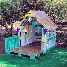 a child's play house made out of pallet wood and painted white, yellow, blue, green and pink