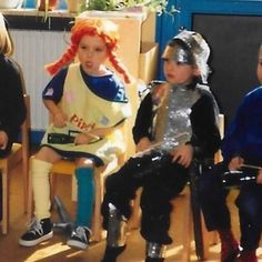 three children in costumes sitting on chairs