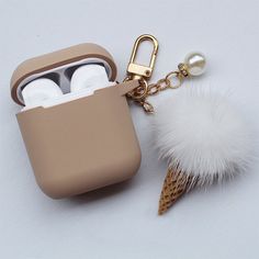 an airpods case with a keychain attached to it and a fur ball hanging from the side