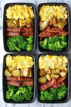 four black plastic containers filled with different types of food and veggies on a marble surface