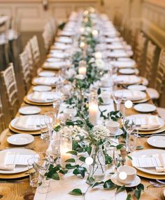 the long table is set with white plates and place settings