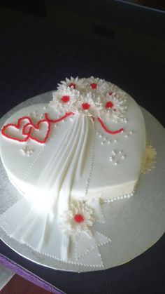 a white cake decorated with red hearts and flowers on a silver platter sitting on a table