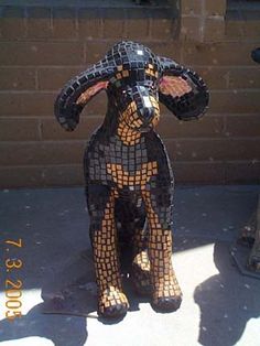 a mosaic dog statue sitting on the sidewalk