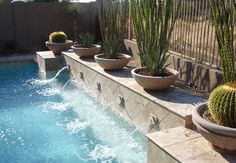 some plants are in large planters next to a small pool with water running through it