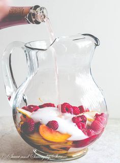 a pitcher filled with fruit and yogurt being poured into it