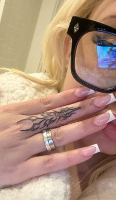 a woman with glasses and tattoos on her hand