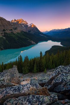 the sun is setting over a mountain lake