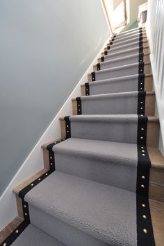 a set of stairs leading up to the top of a staircase with black and white carpet