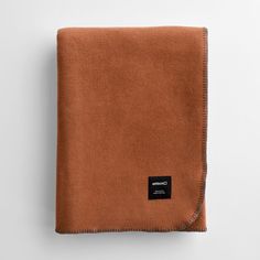 a brown blanket folded on top of a white surface with a black label in the middle