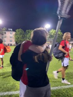 two people hugging each other on a soccer field at night with lights in the background