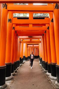 a woman walking down a path lined with tall orange pillars