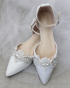 a pair of white wedding shoes with crystal embellishments on the toes and heel