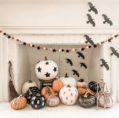 a fireplace decorated for halloween with black and white pumpkins, jack - o'- lanternes and bats