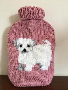 a pink knitted hot water bottle with a white dog on it