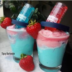 two drinks with strawberries on the rims and one has blue liquid in it