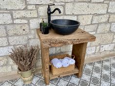 a bathroom sink sitting on top of a wooden table next to a potted plant