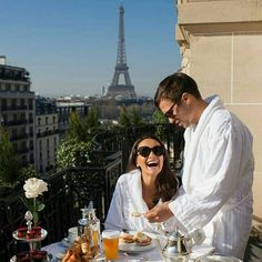 a man and woman sitting at a table with food in front of the eiffel tower