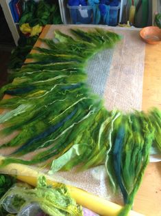 green and yellow feathers are laid out on a table with other items in the background