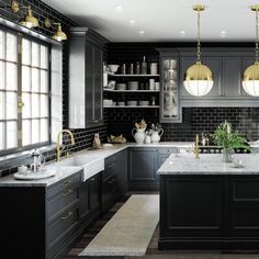 a large kitchen with black cabinets and white counter tops, along with an island in the middle