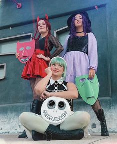 three women dressed up in costumes posing for the camera with one holding a fake skull