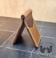 two pieces of brown leather sitting on top of a tile floor