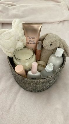 a basket filled with personal care items on top of a white sheet covered bed next to a stuffed animal