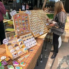 a woman standing next to a table filled with lots of magnets on it's sides