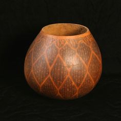 an orange and brown vase sitting on top of a black surface