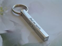 a metal keychain with a message on it sitting on a flowery surface