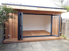 an outdoor room with wooden flooring and doors open to reveal a large area that has been built into the ground