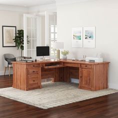 a wooden desk sitting on top of a hard wood floor next to a white wall