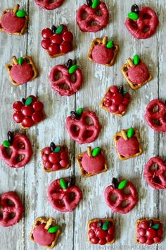 there are many red treats on the table with apples and pretzels in them