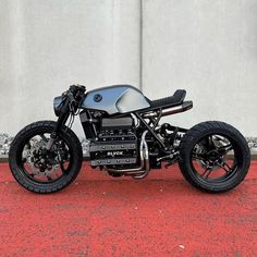 a motorcycle parked on the side of a road next to a wall and red carpet