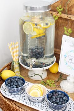 blueberries, lemons and water in bowls on a table with a glass jar